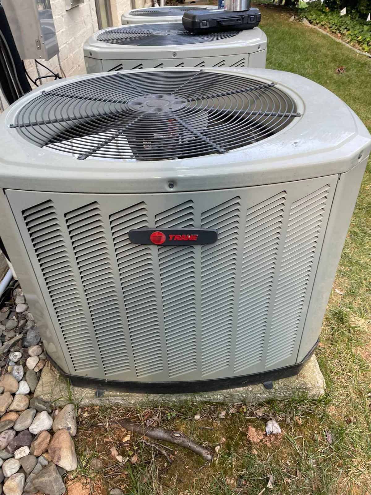 Three Trane air conditioning units, gray, outdoors.