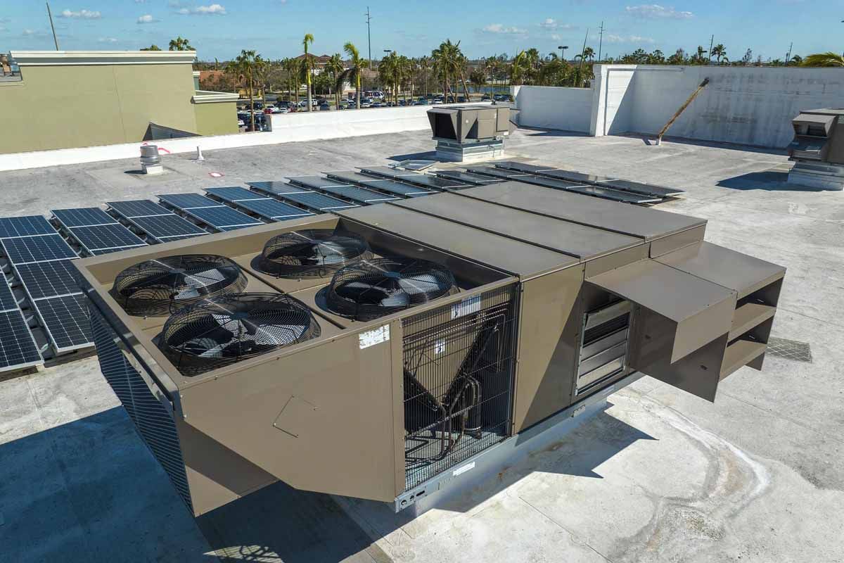 Rooftop HVAC unit with multiple fans and solar panels, sunny day.