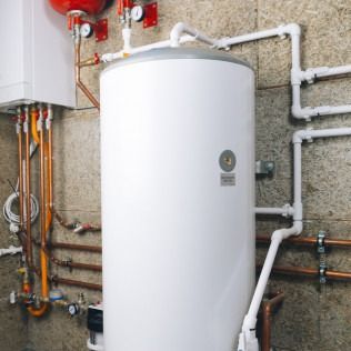 White water heater and associated plumbing against a beige wall.