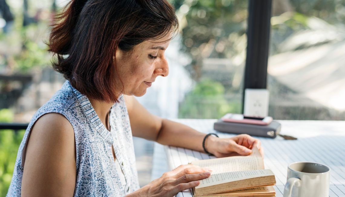 Mujer leyendo un libro en un espacio tranquilo con luz natural, imagen para blog sobre libros que ac