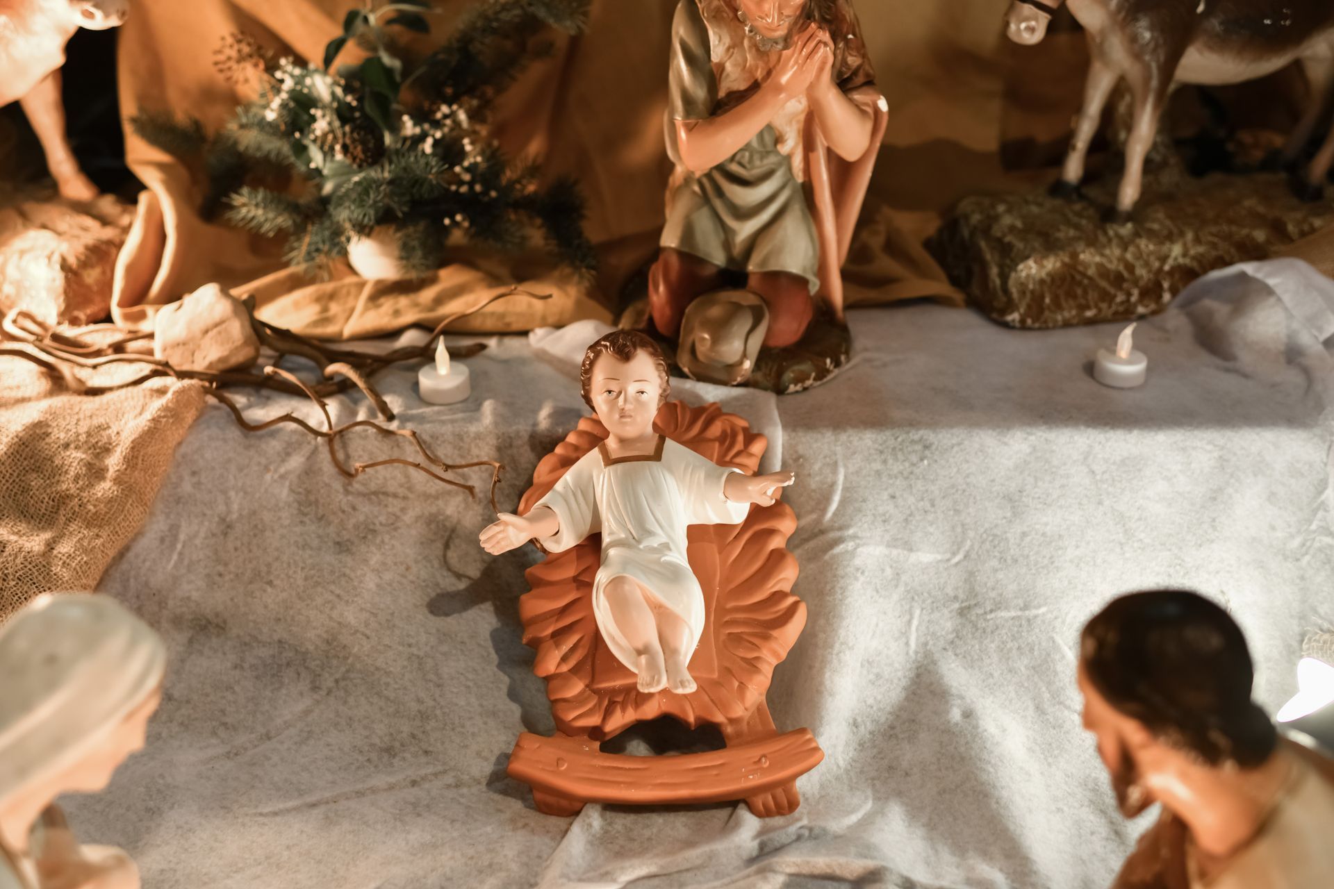 Nacimiento navideño con figuras de José, María y el Niño Jesús en su pesebre, ambientado con decoración natural y cálida iluminación.