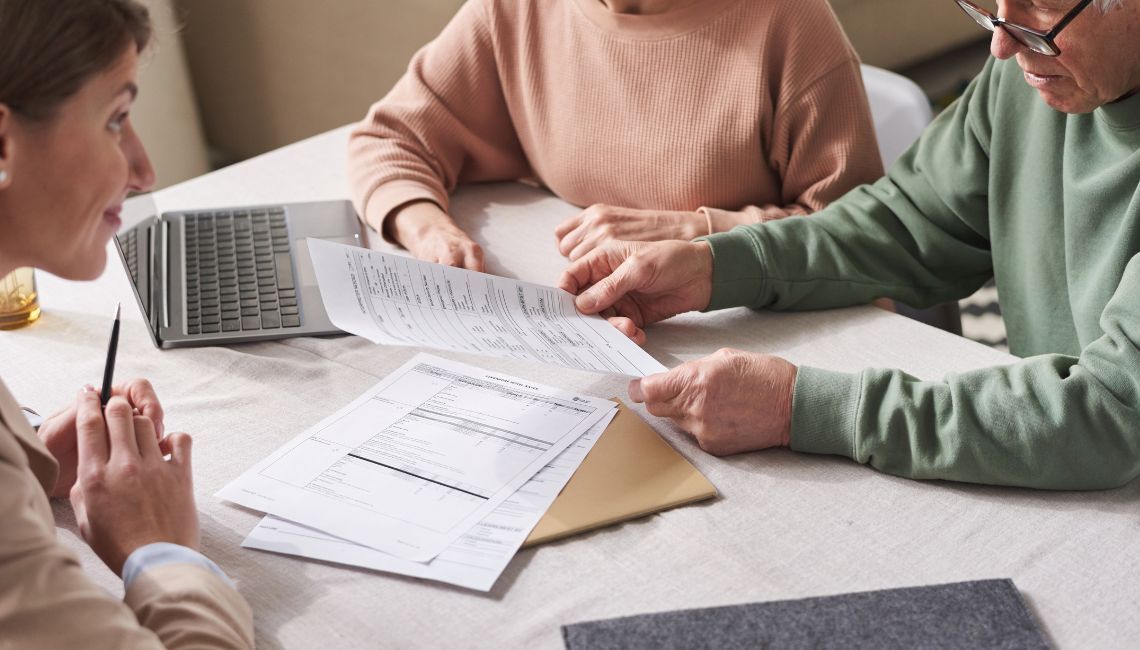 Manos de varios familiares revisando documentos y tomando decisiones alrededor de una mesa.