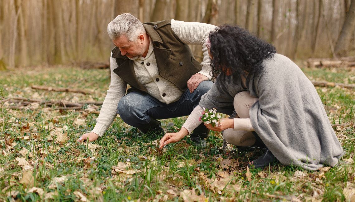 Pareja de adultos colocando flores silvestres en un bosque como homenaje ecológico a un ser querido