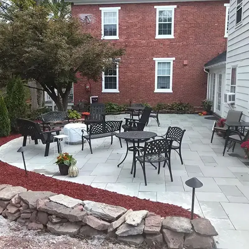 Patio with black metal tables and chairs, stone border, and red brick building backdrop