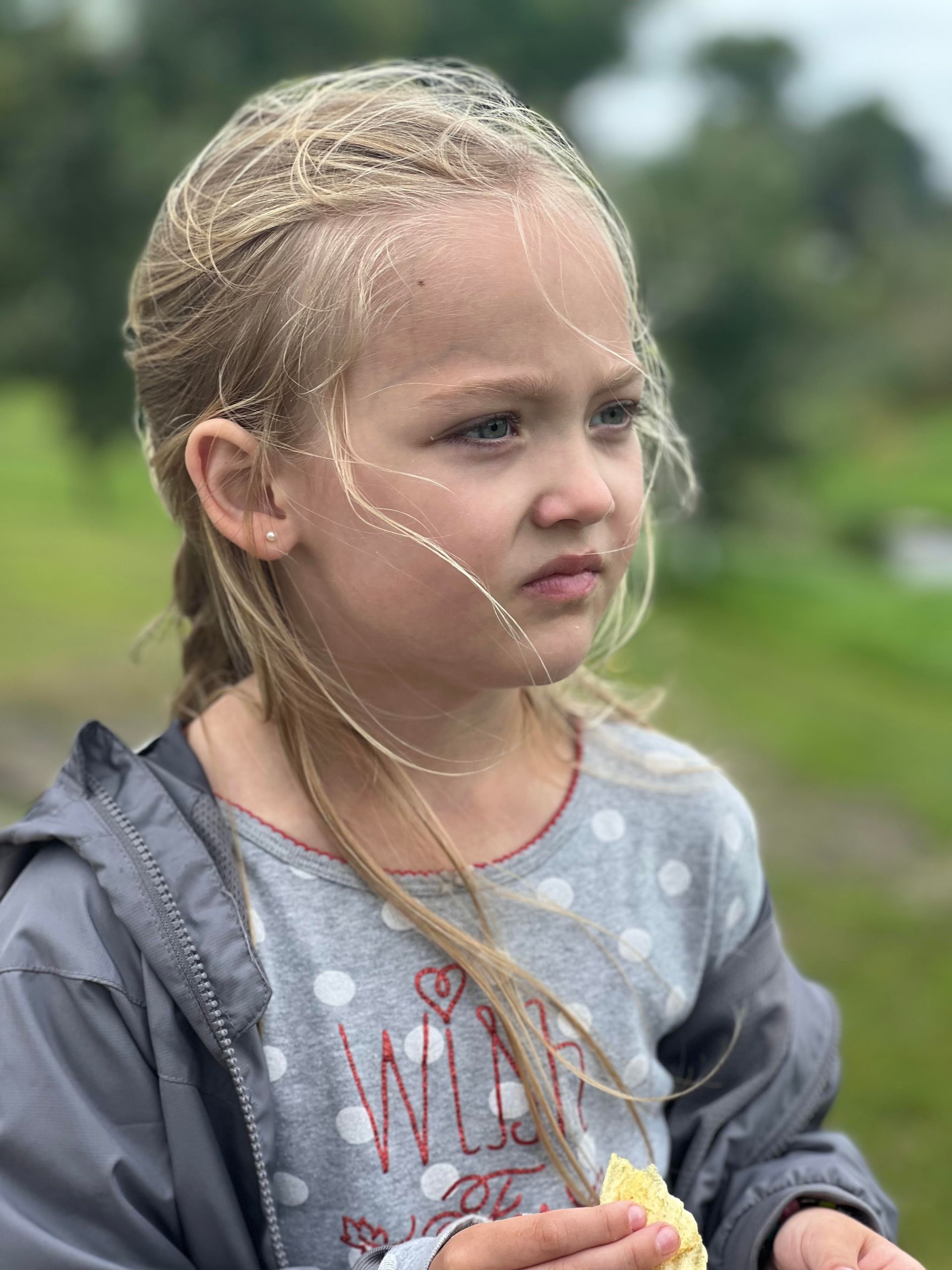A little blonde girl staring at something in the distance