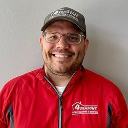 a man wearing a red jacket and a hat is smiling for the camera .
