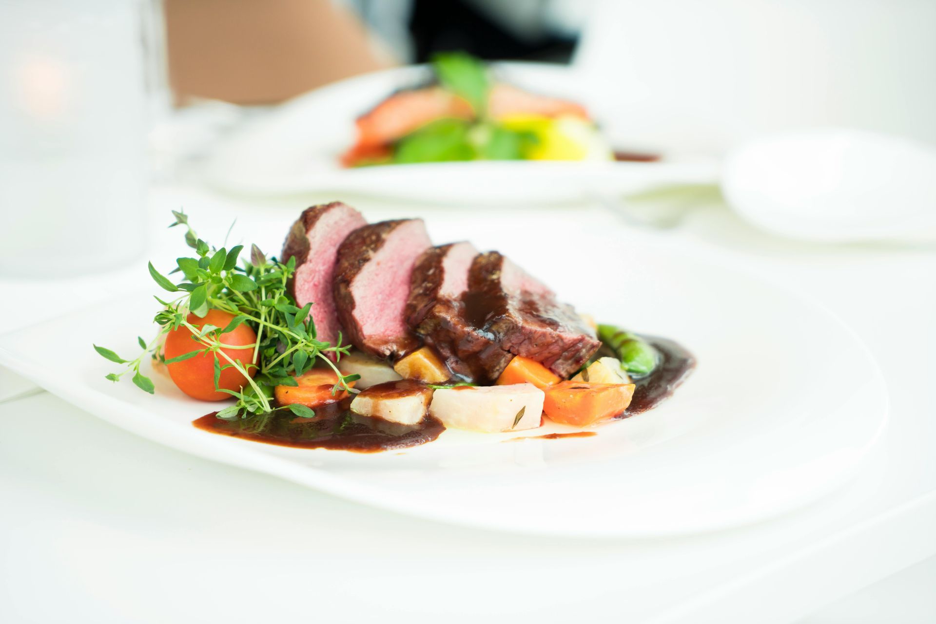 A white plate topped with meat and vegetables on a table.