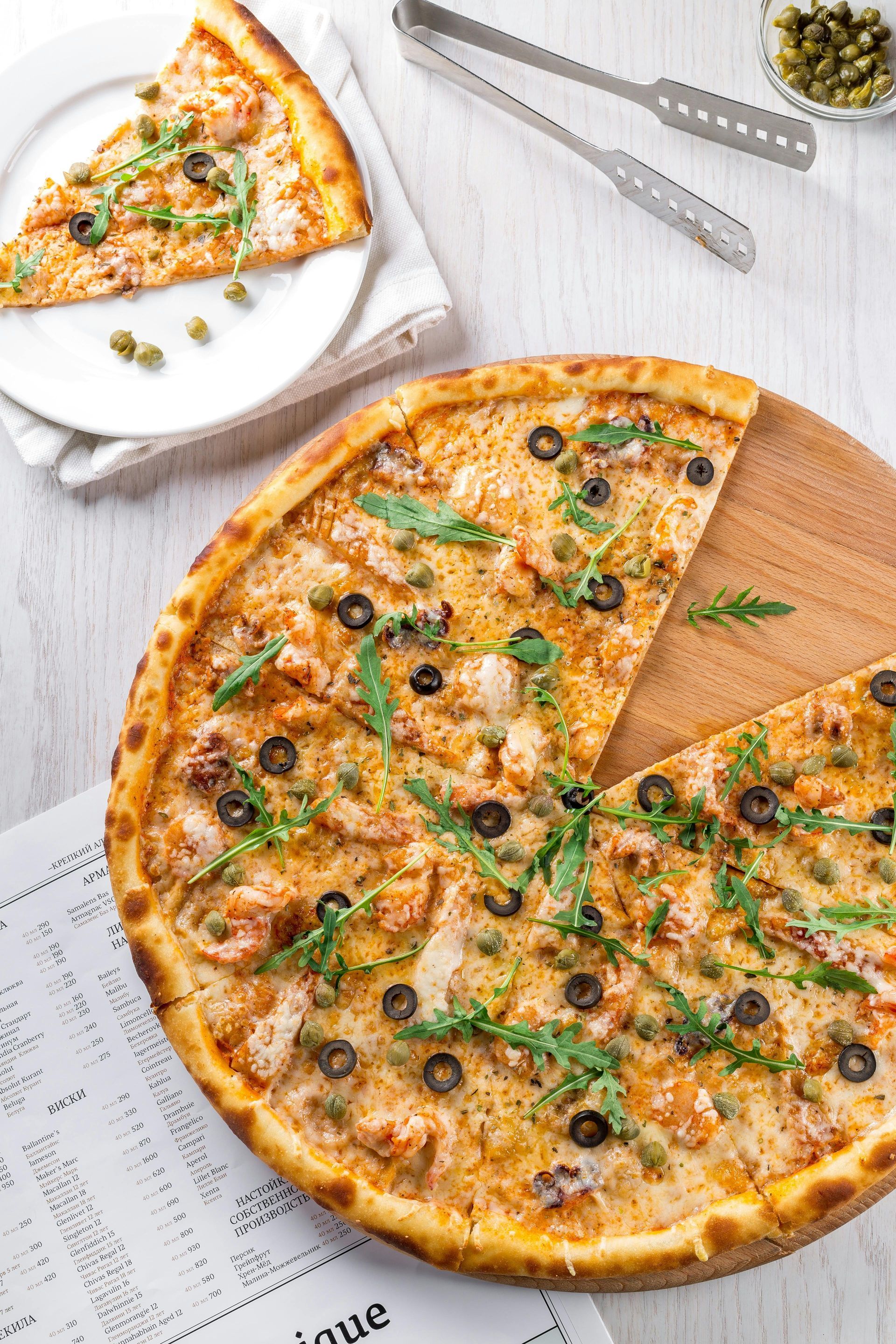 A pizza with a slice taken out of it is on a wooden cutting board.