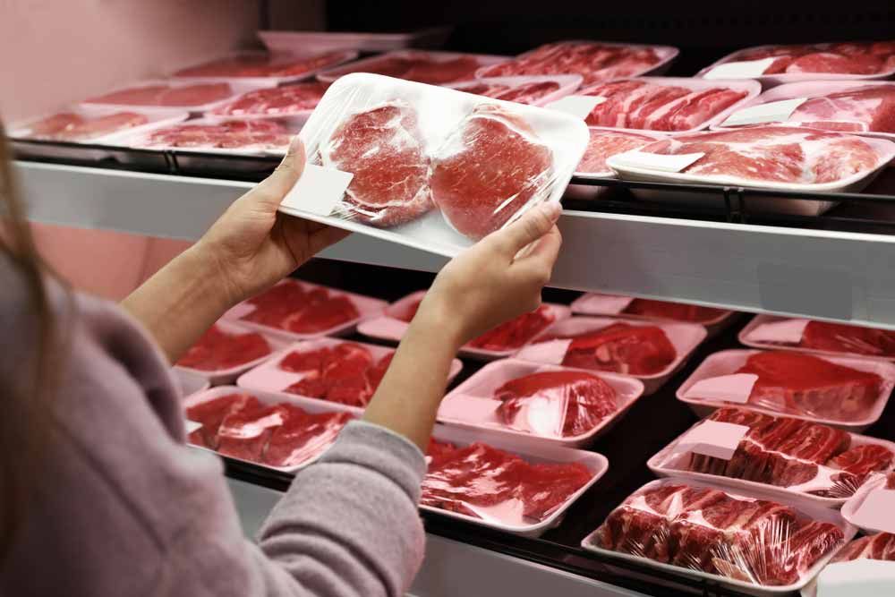 Woman Looking A Wrapped Meat From A Retail Shelf