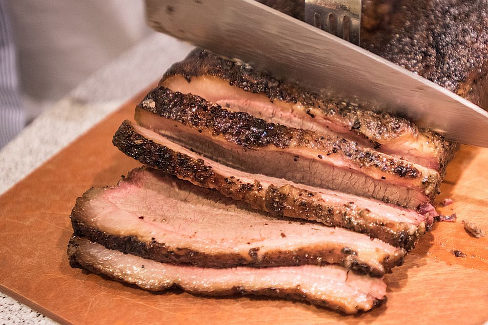 Barbecue beef brisket being cut on cutting board — Wholesale Butchery in Nyngan, NSW
