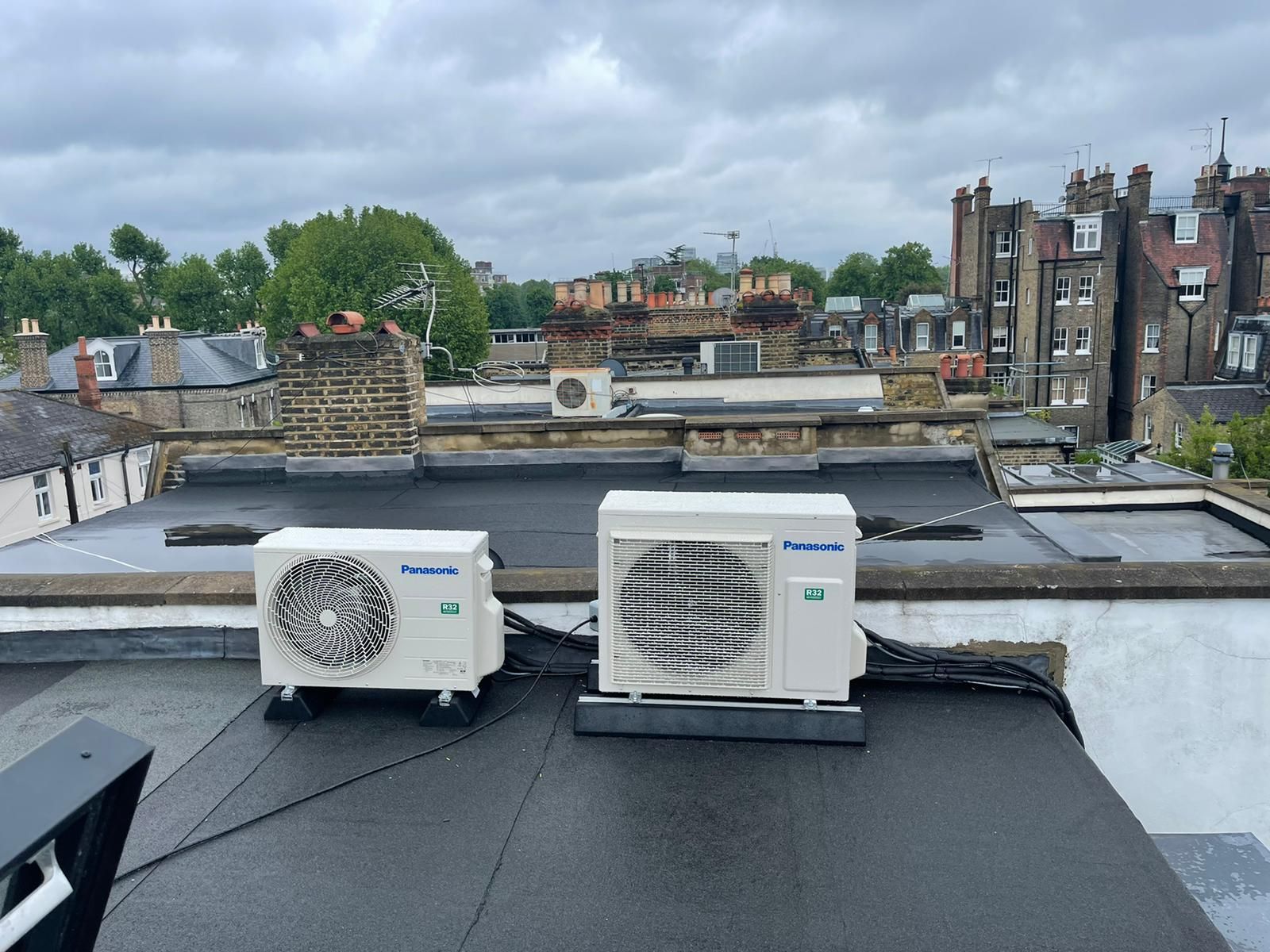 Two air conditioners are sitting on top of a roof.