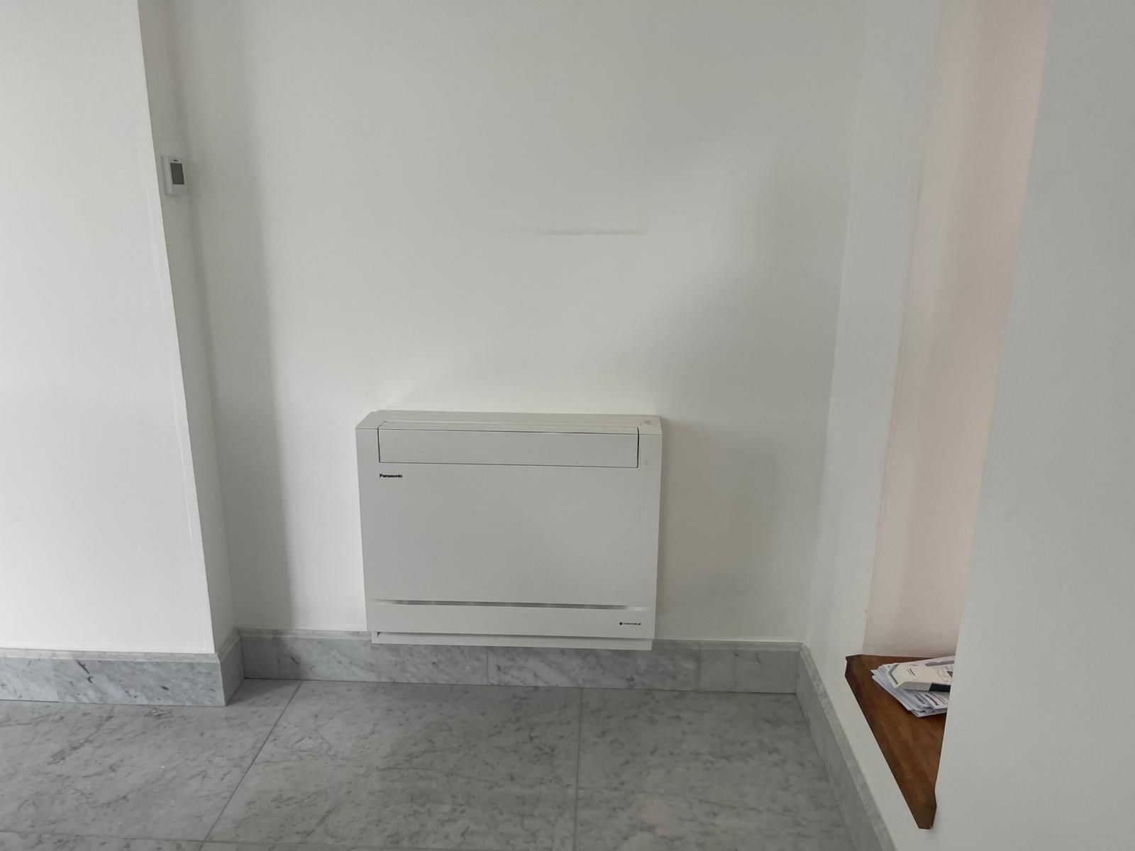 A white box is hanging on a white wall in a room.
