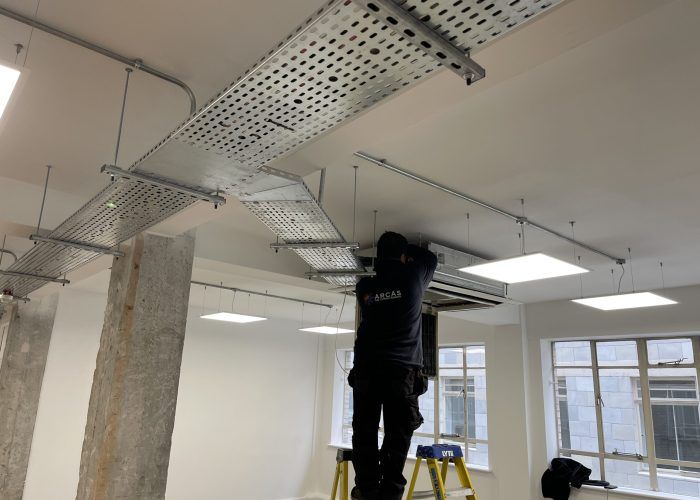 A man is standing on a ladder working on a ceiling.