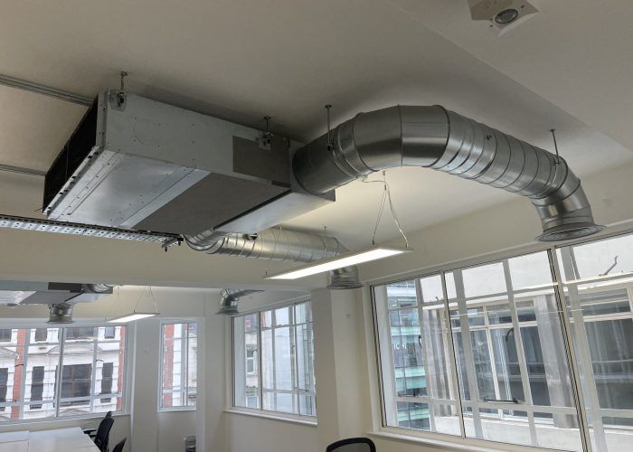 A room with a lot of windows and a metal pipe hanging from the ceiling.
