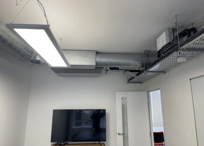 A room with a flat screen tv hanging from the ceiling.
