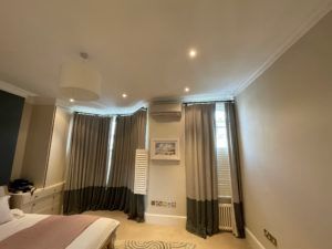 A bedroom with a bed , curtains and a television.
