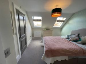 A bedroom with a bed and a skylight on the ceiling