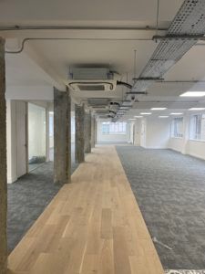 A long hallway with wooden floors and a ceiling fan.