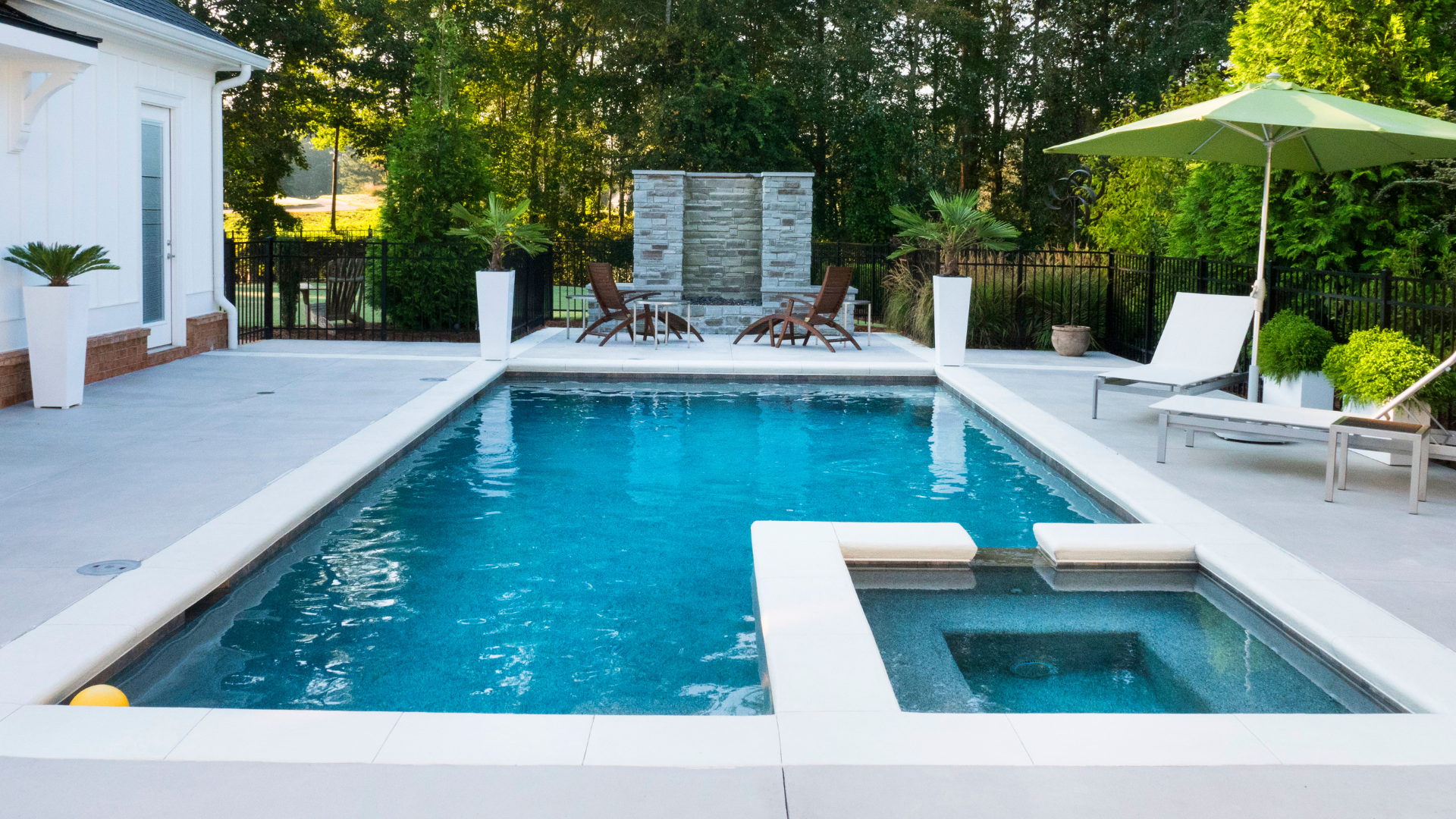 There is a large swimming pool in the backyard of a house.