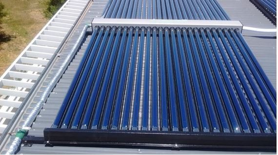 Tubos solares térmicos azules en una instalación en el tejado, iluminados por la luz del sol, vistos desde arriba.