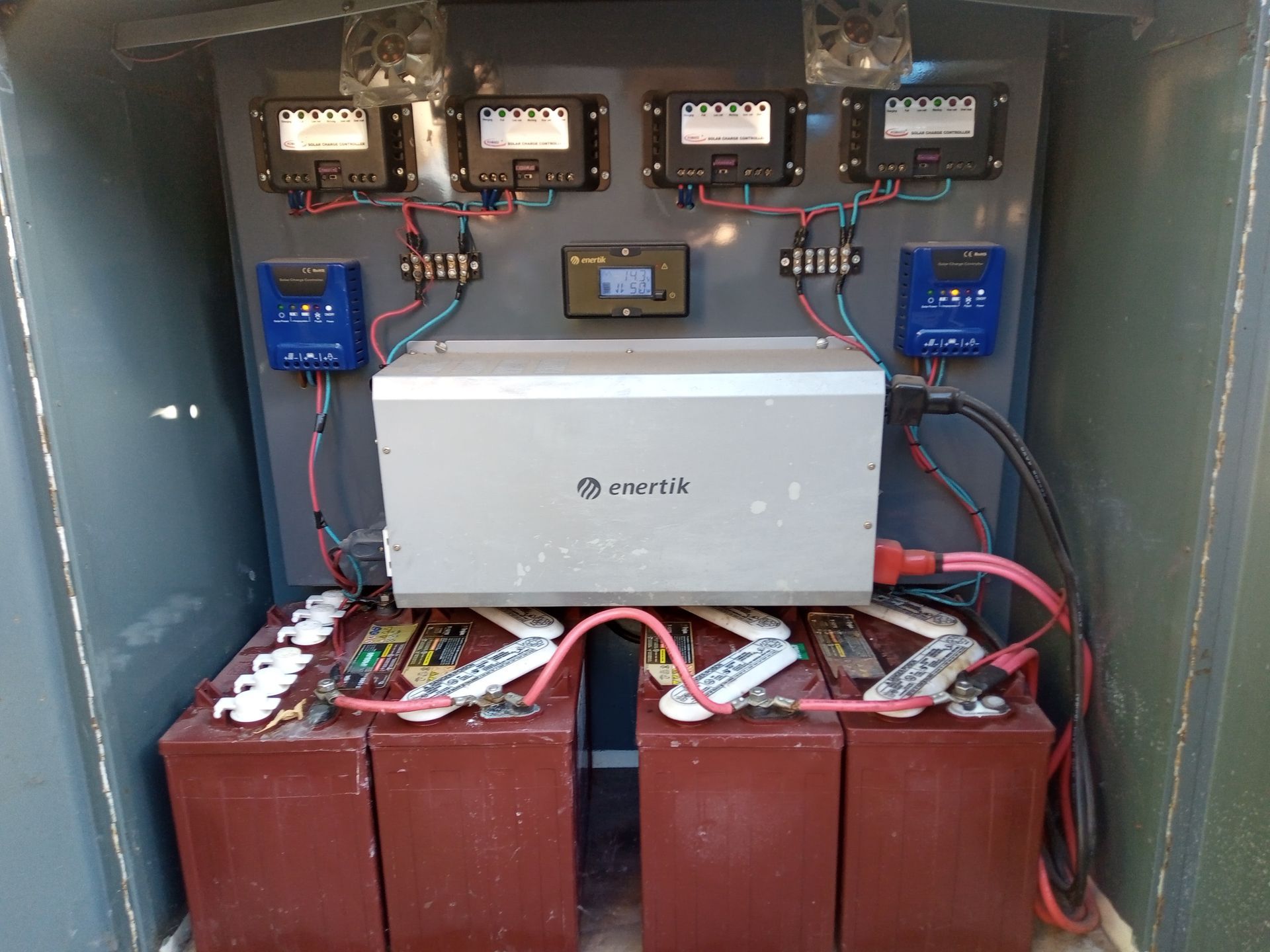 Armario de control eléctrico con baterías, inversor y cableado dentro de una carcasa metálica.