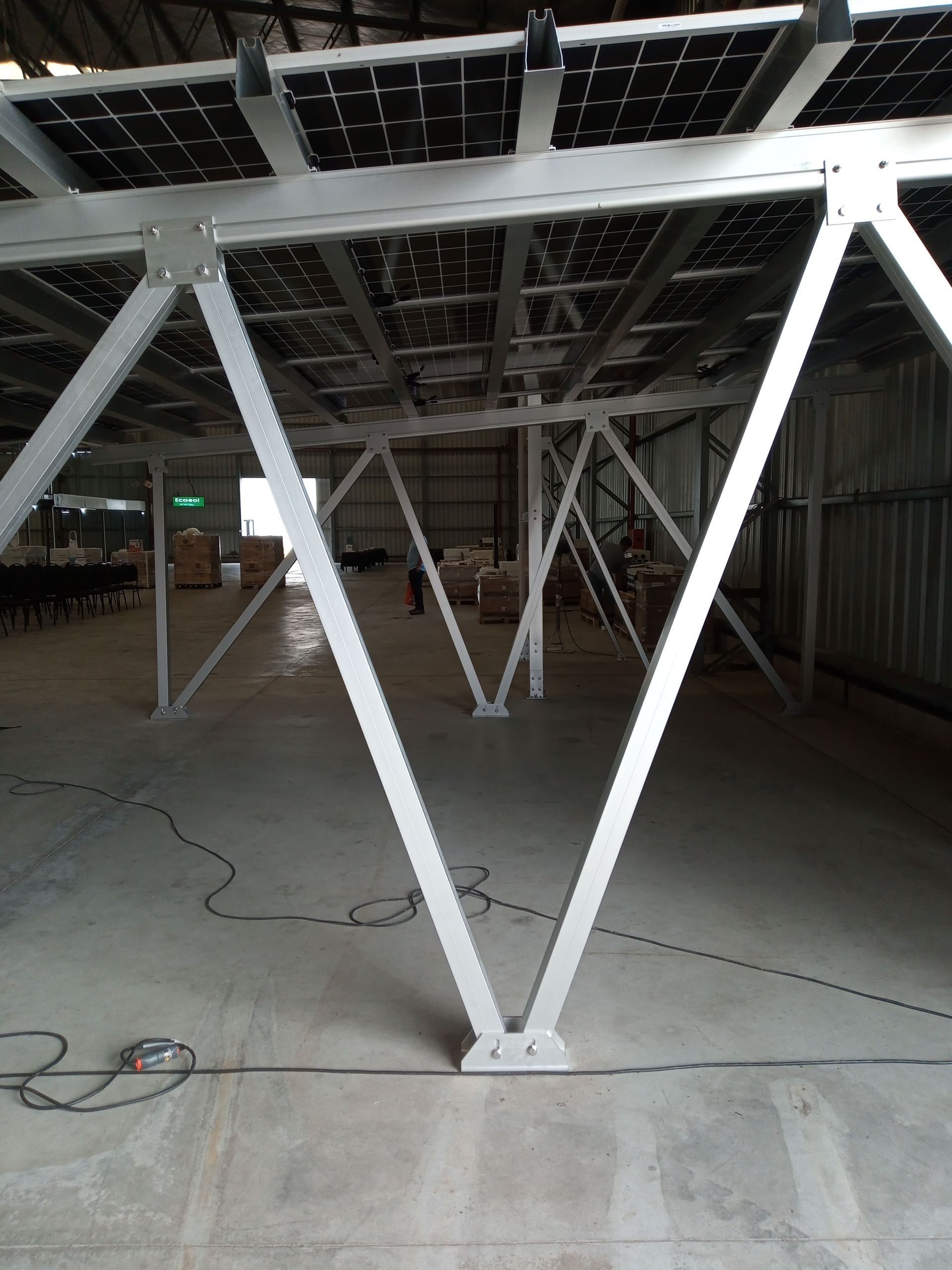 Estructura de acero blanco en el interior de un almacén sin terminar, con suelo de hormigón y vigas de techo a la vista.