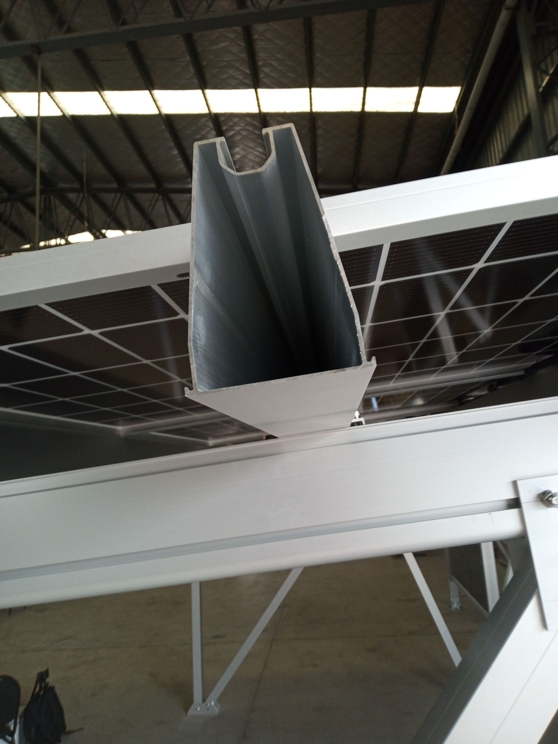 Primer plano del extremo de una viga de metal gris en el techo de un almacén industrial.