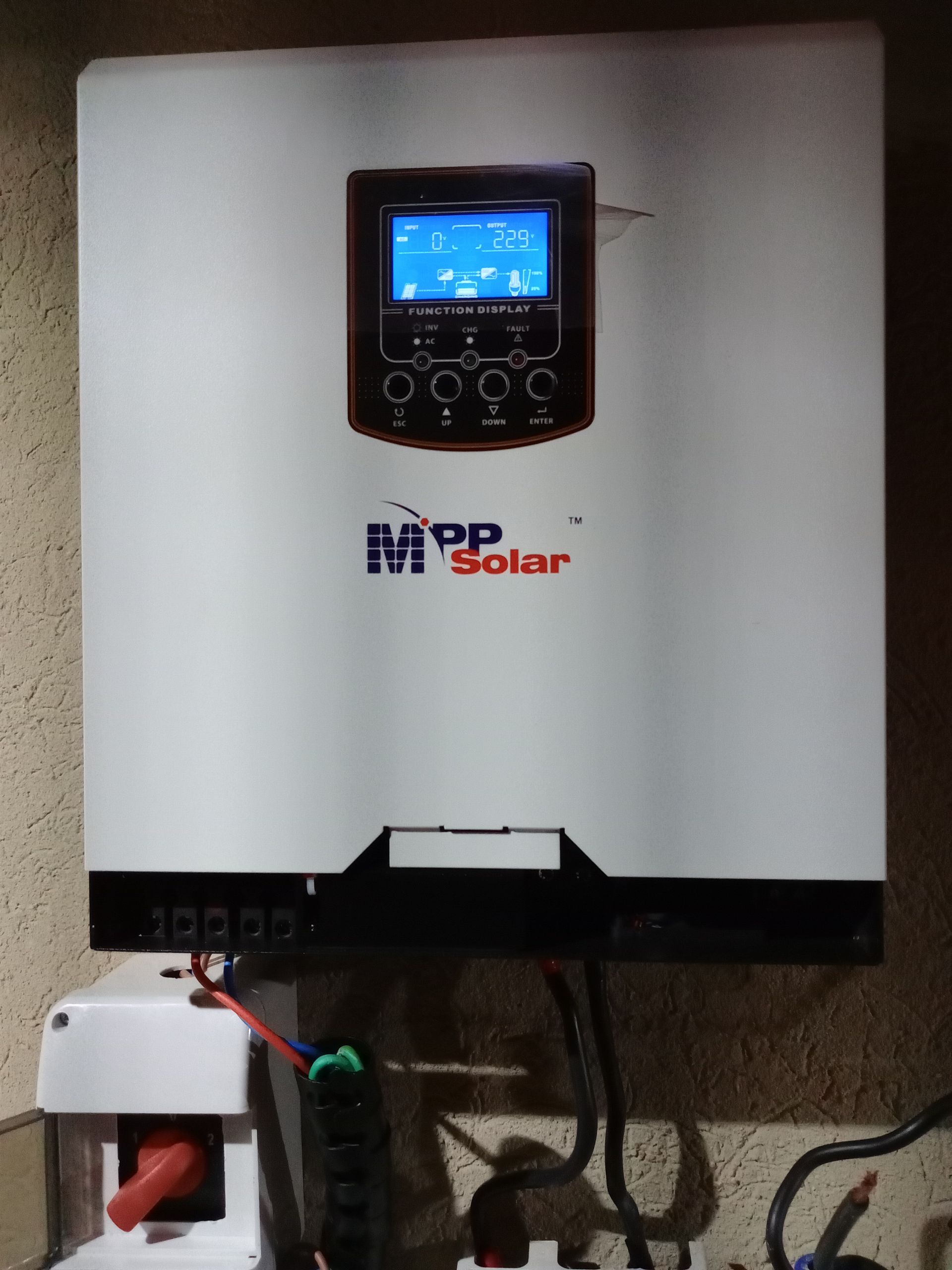 Inversor solar MPP blanco montado en la pared con pantalla azul iluminada y cables conectados debajo.