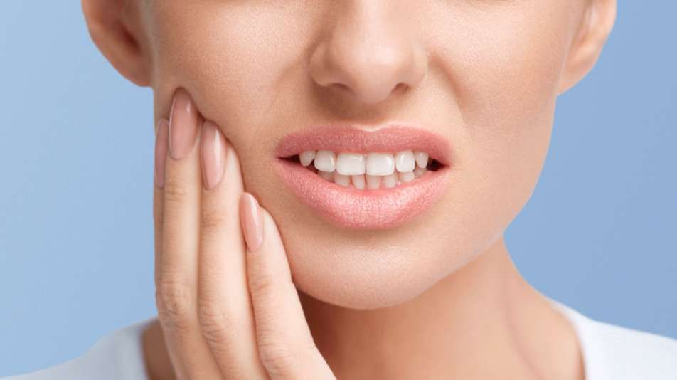 A woman is holding her mouth in pain because of a toothache.