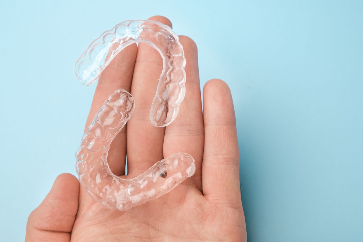 A person is holding a clear mouth guard in their hand.