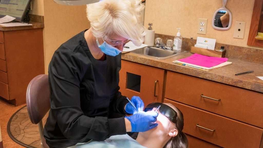 A dentist is examining a patient 's teeth in a dental office.