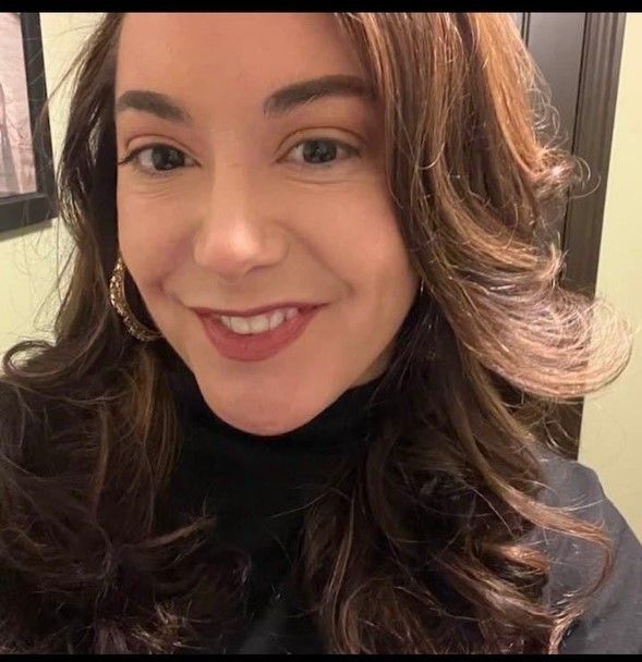 A woman with long brown hair is smiling for the camera.
