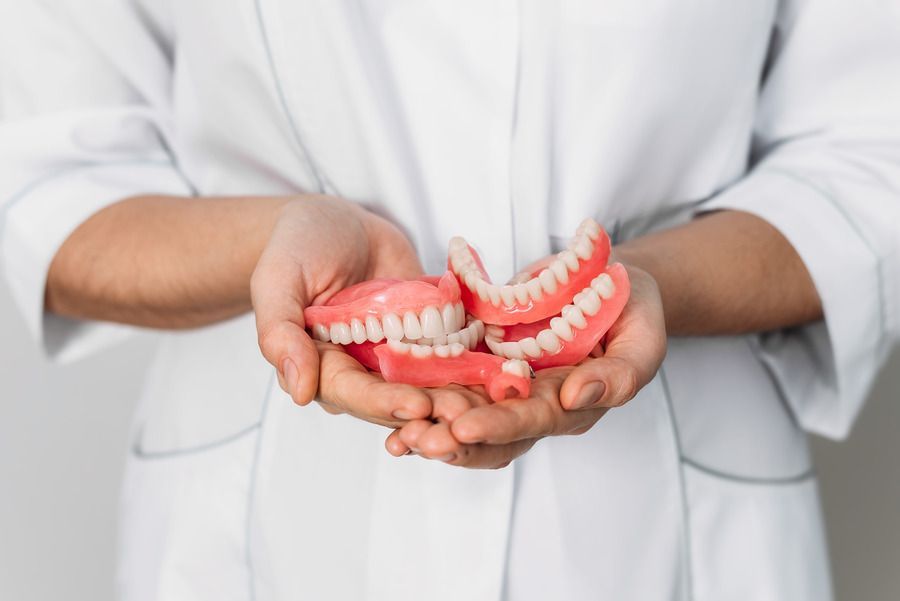 A dentist is holding a model of dentures in his hands.