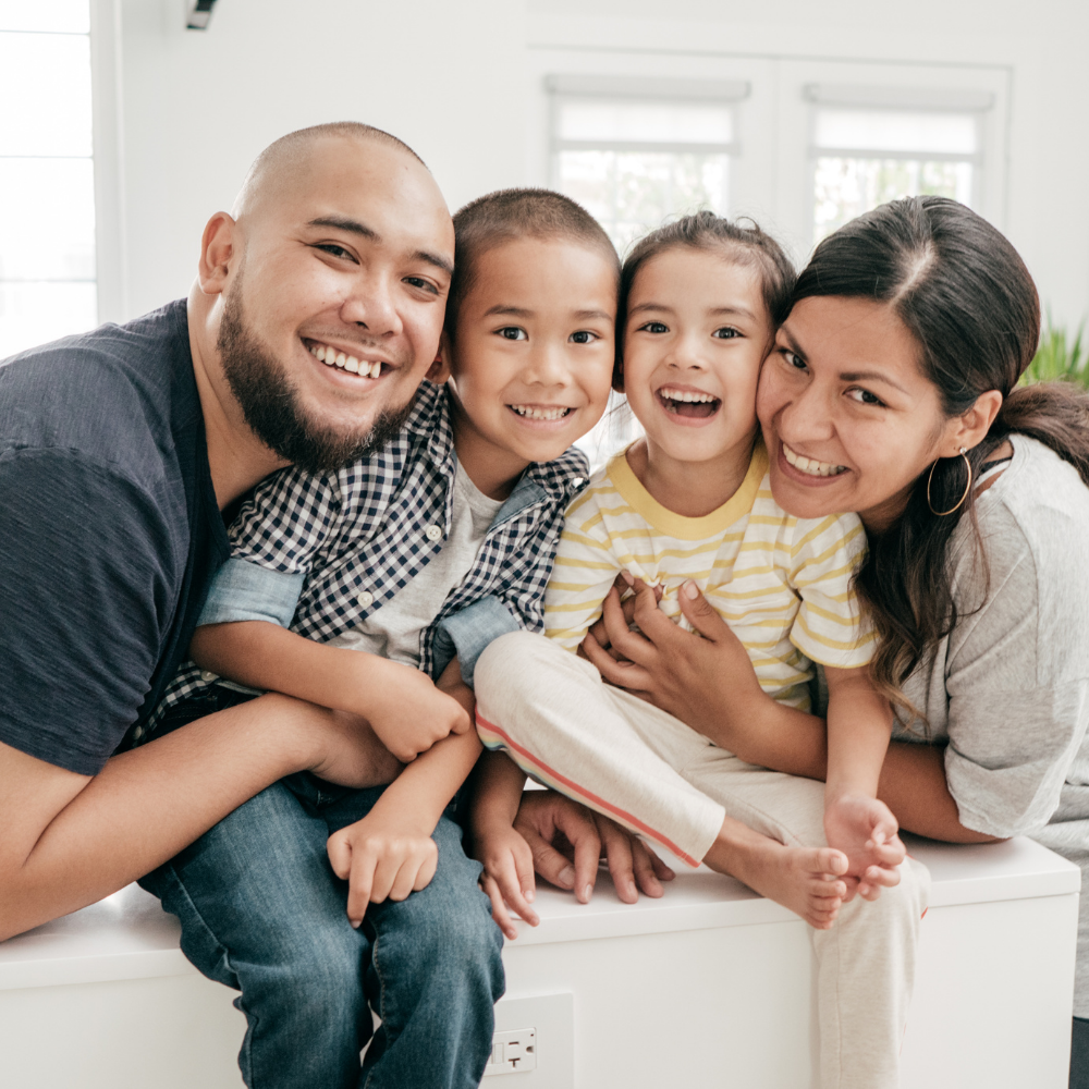 A family is posing for a picture while sitting on a bench.