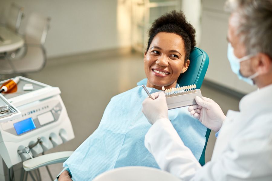 A woman is sitting in a dental chair talking to a dentist.