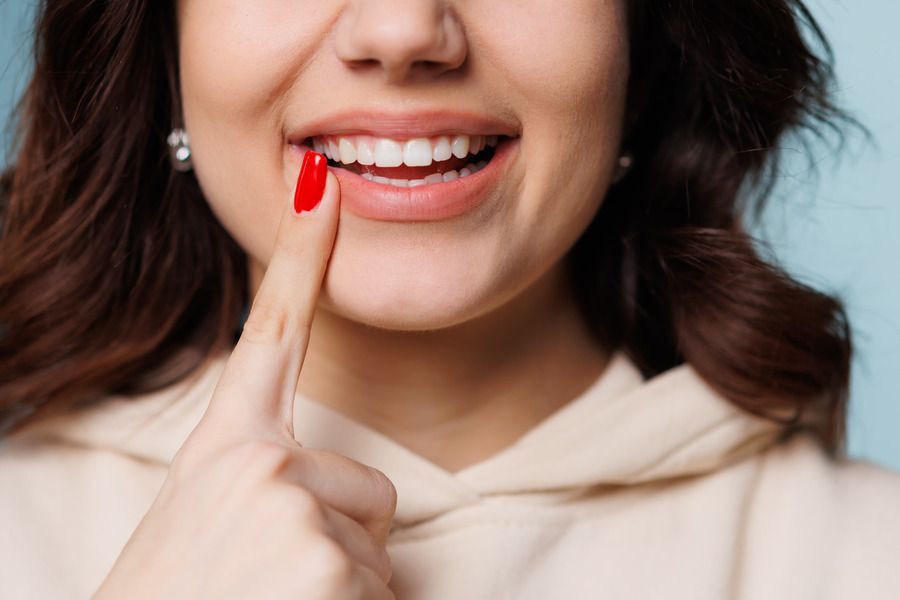 A woman is holding a red candy in her mouth.