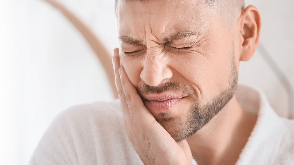 A man is holding his face in pain because of a toothache.