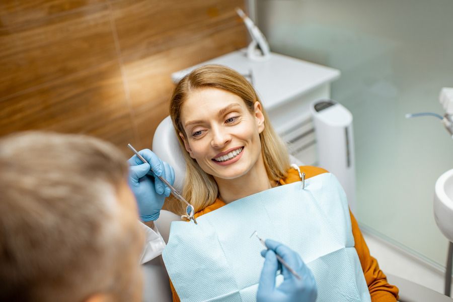 A woman is smiling while sitting in a dental chair.