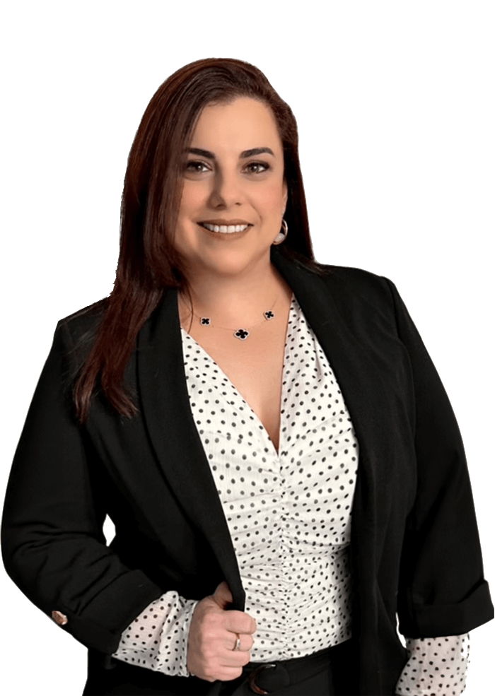 Woman smiling, wearing black blazer over a polka-dot shirt, posing for the camera.