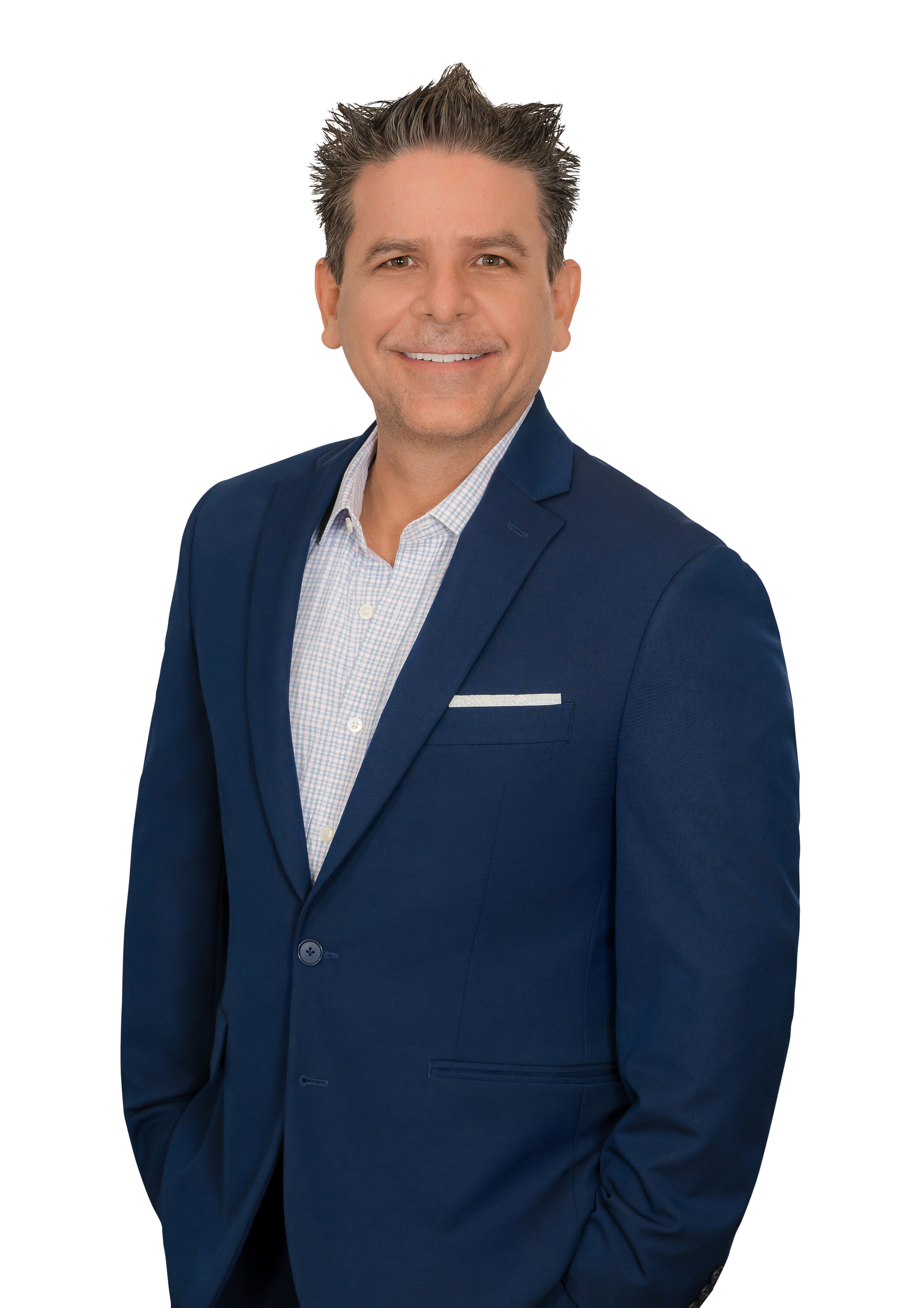 Man in blue suit, hands in pockets, smiling, against a white background.