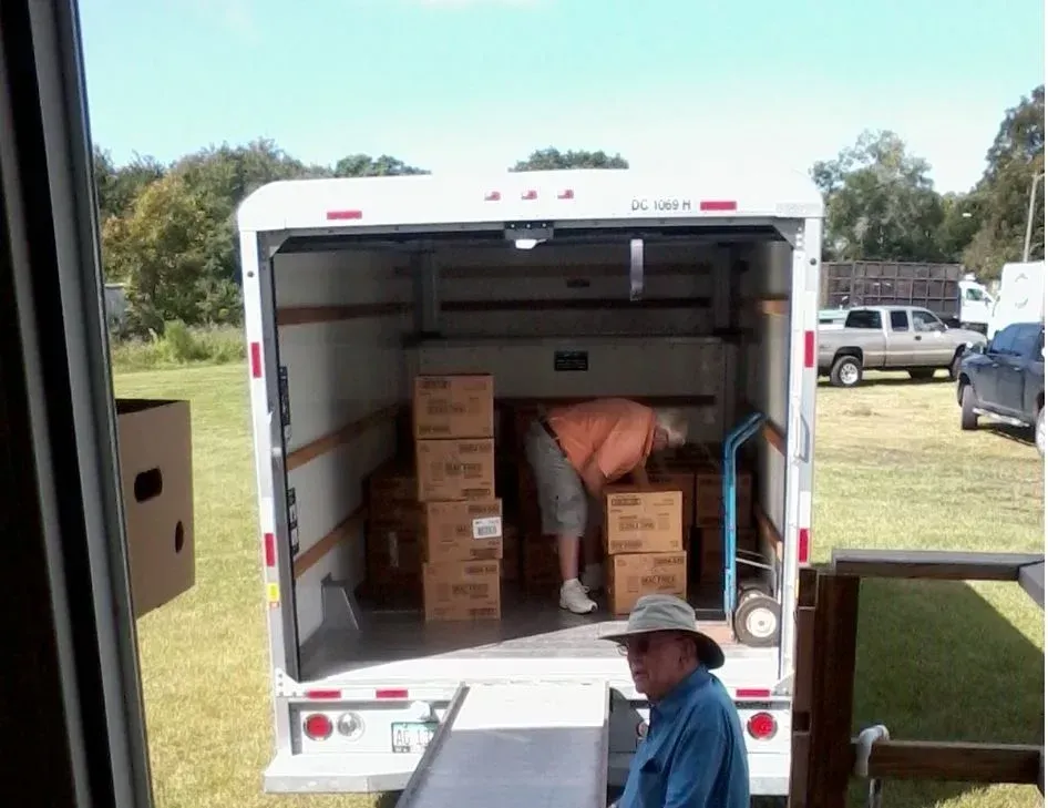A man in a hat is looking into the back of a moving truck