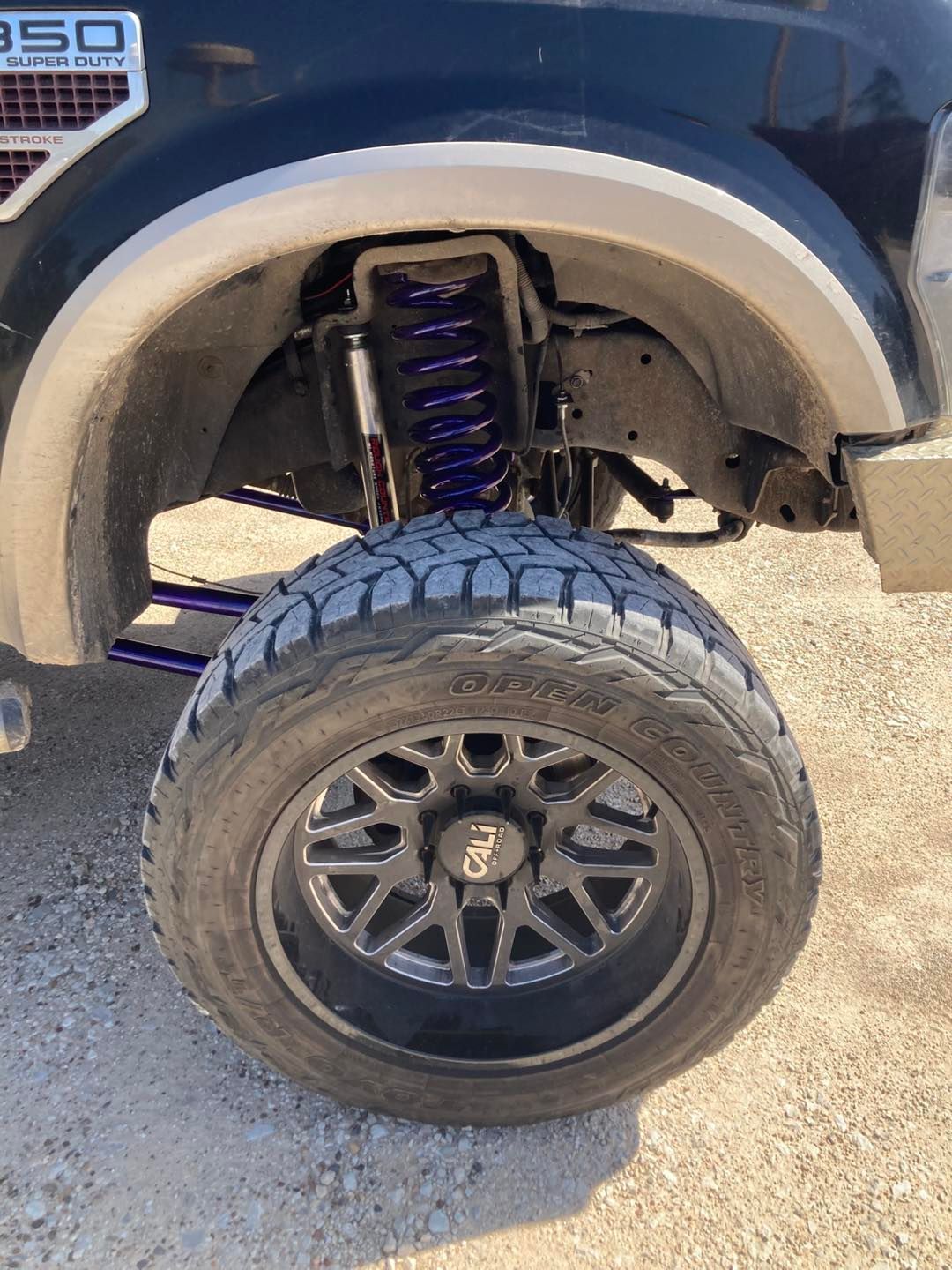 Black truck tire and rim with purple suspension components.