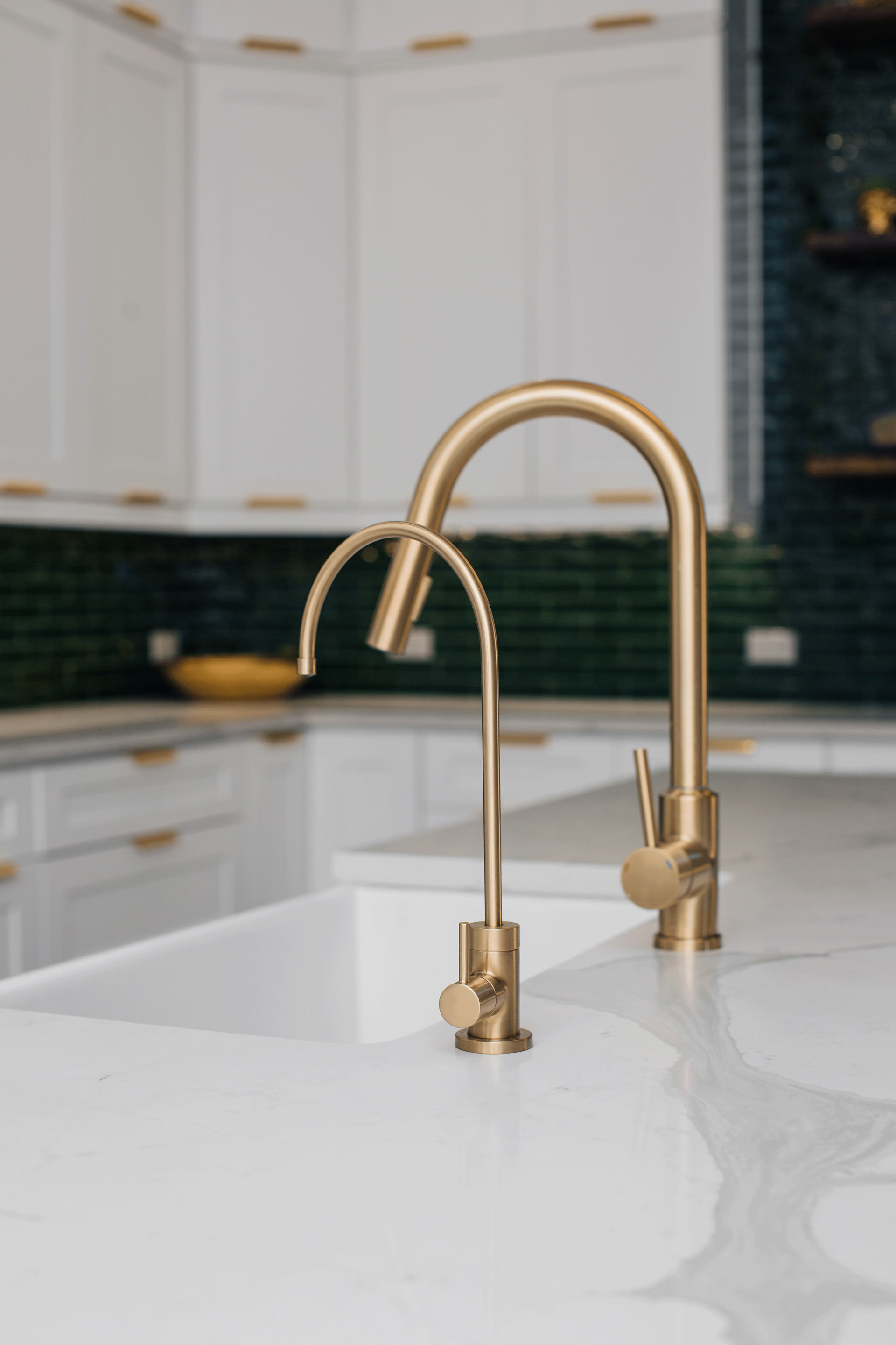 A kitchen sink with two gold faucets on it.