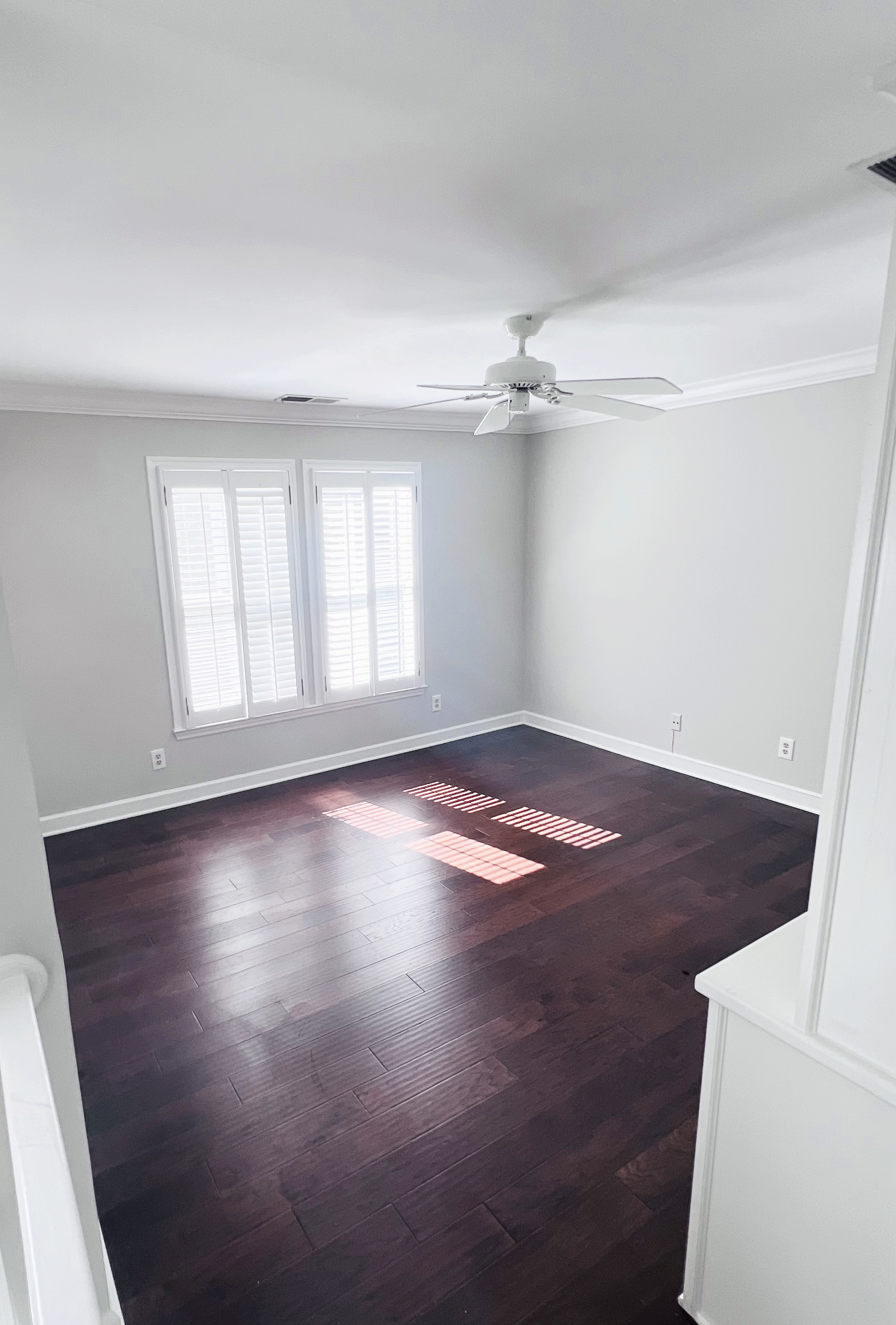 An empty living room with hardwood floors and a ceiling fan.