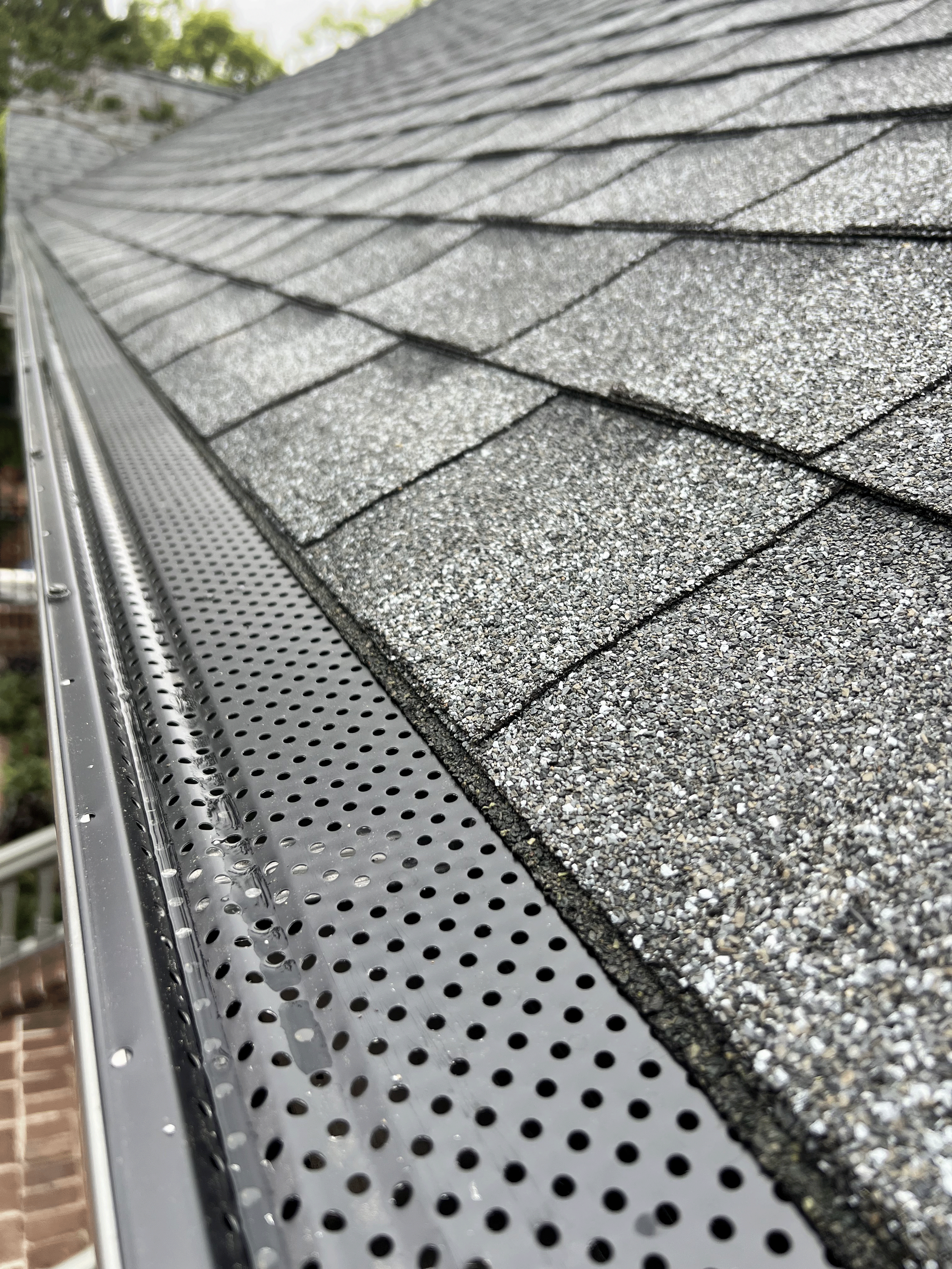 A close up of a gutter on a roof with shingles.