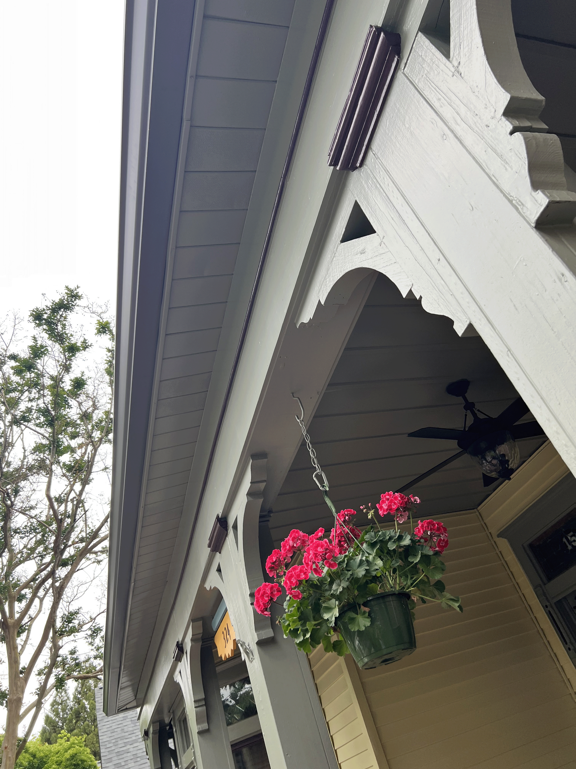 A porch with a hanging basket of flowers and a ceiling fan