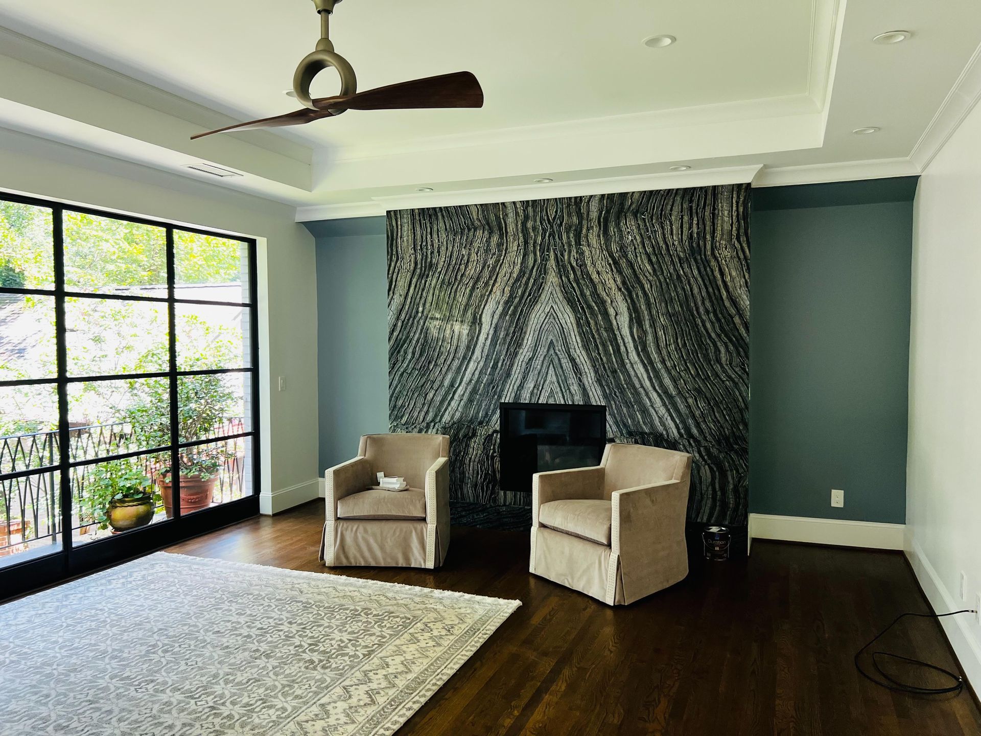 A living room with two chairs , a fireplace and a ceiling fan.
