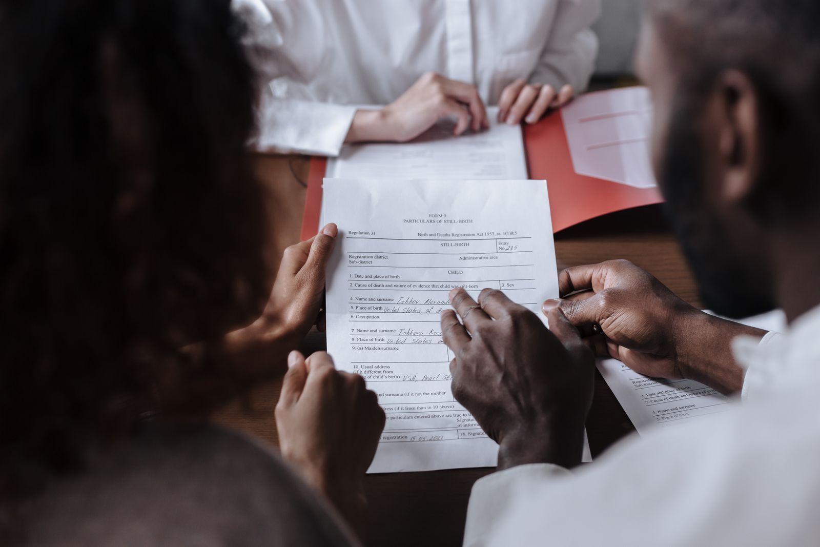 People reviewing a document together at a table, with hands pointing at the paper in a meeting.