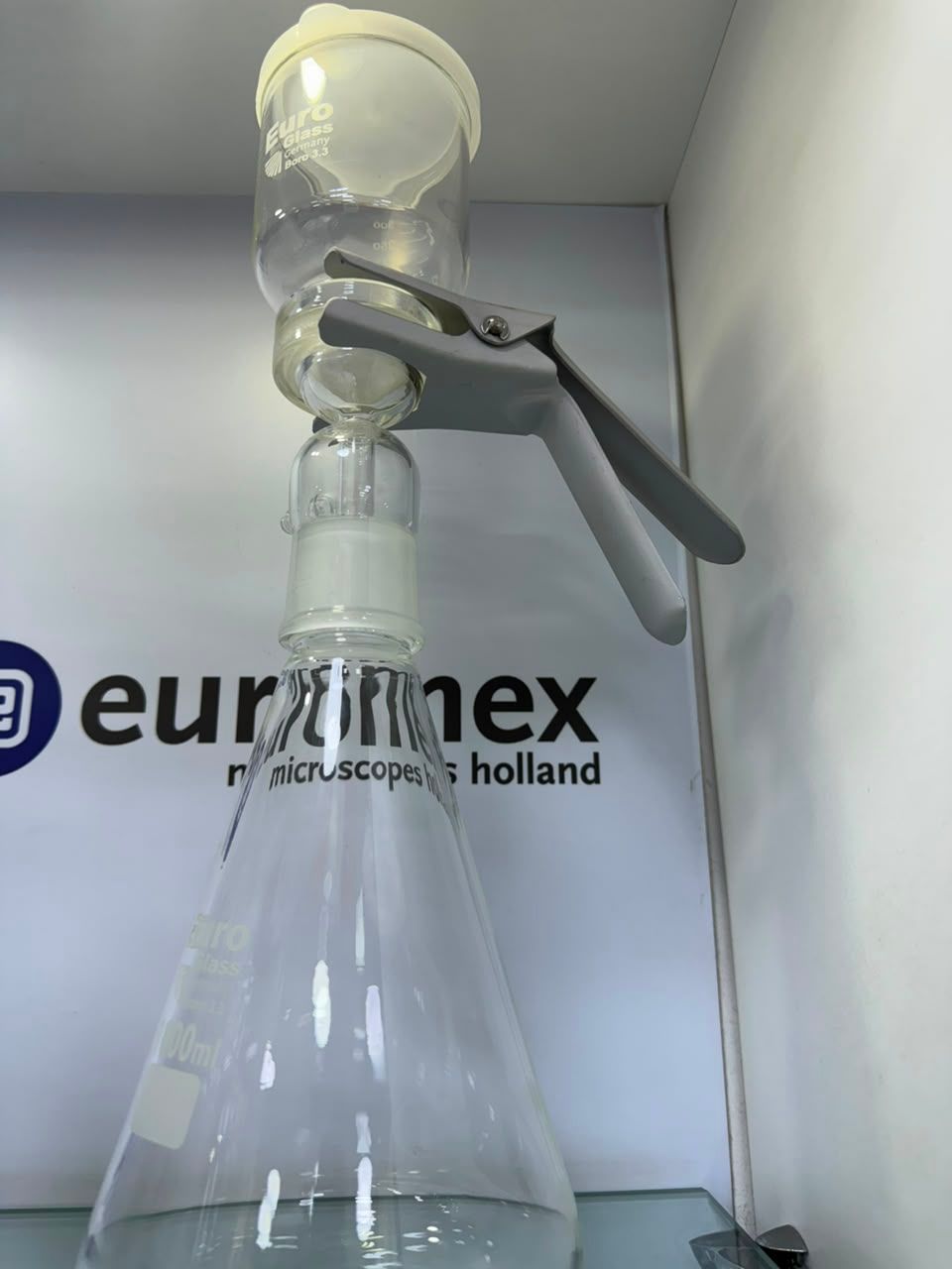 Montaje de material de vidrio de laboratorio con una pinza que sujeta un embudo sobre un matraz 
