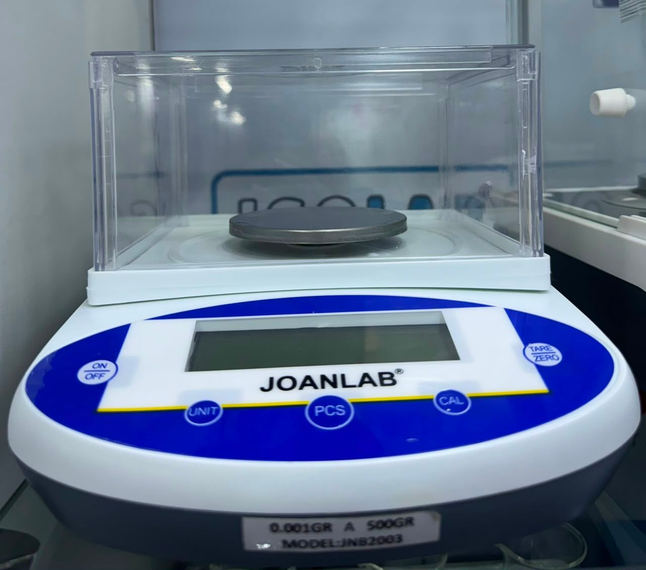 Balanza digital de laboratorio con carcasa de plástico transparente y plato en la plataforma de pesaje